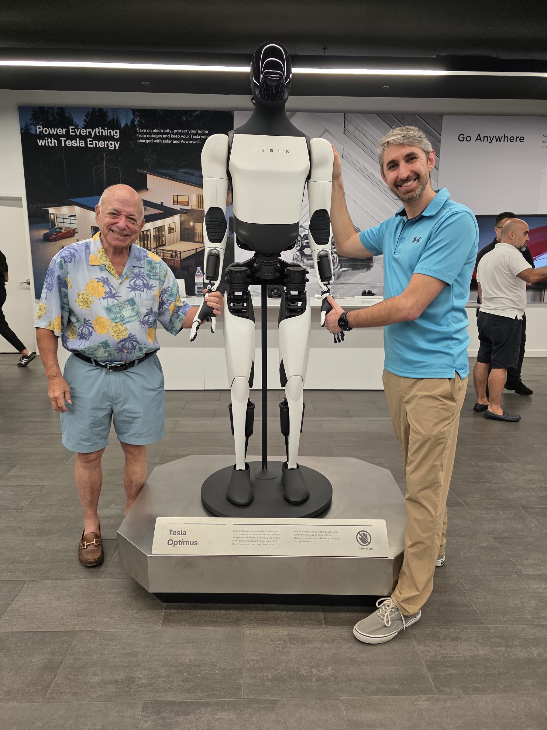 Bob Leaf beside a humanoid robot on display, with a companion.